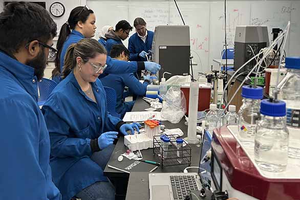 students in lab coats working in lab